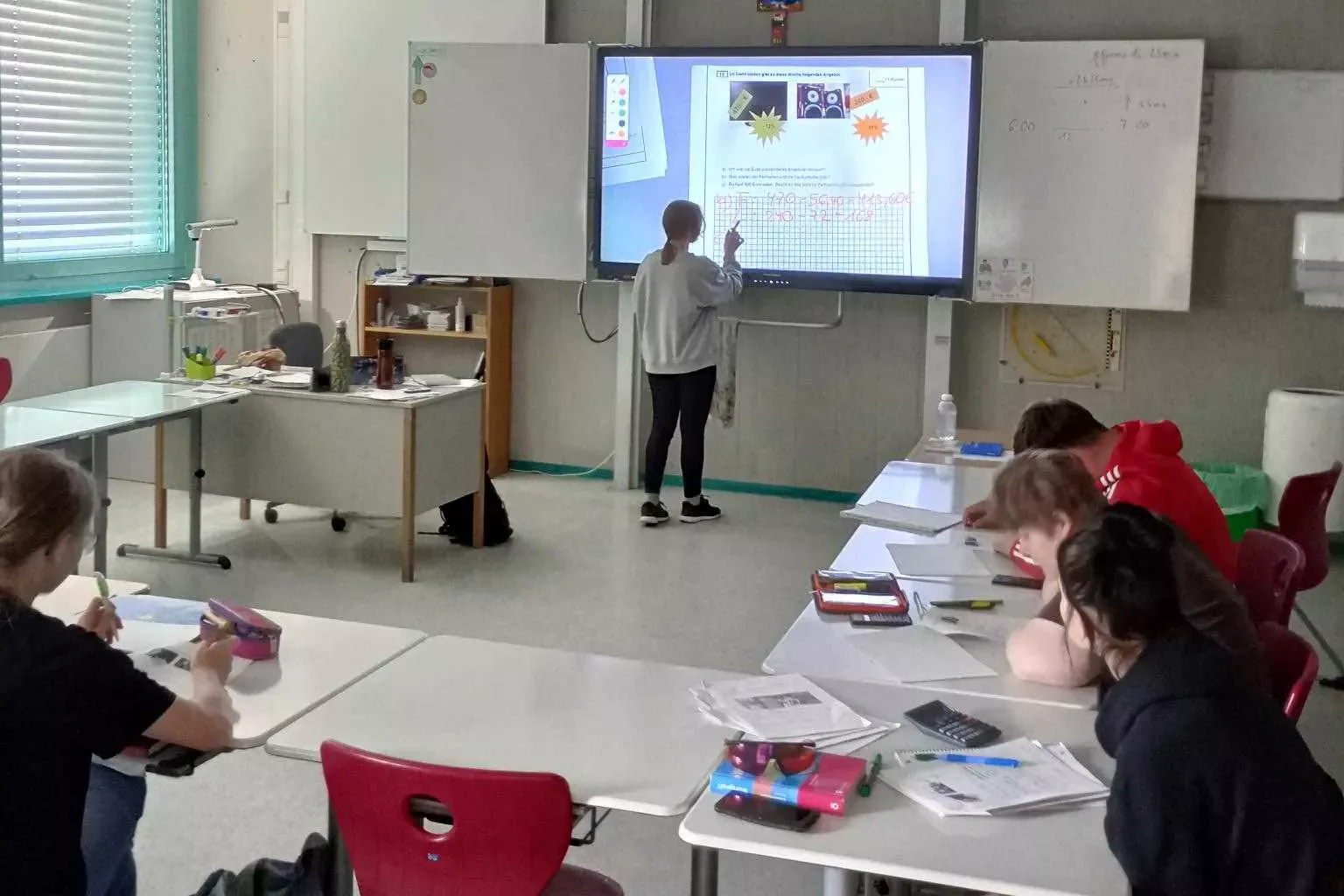 Schüler im Klassenzimmer lernen in den Ferien, beschreiben eine digitale Tafel